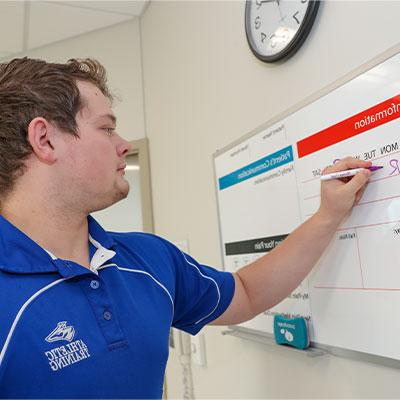 a student writes on a dry erase board